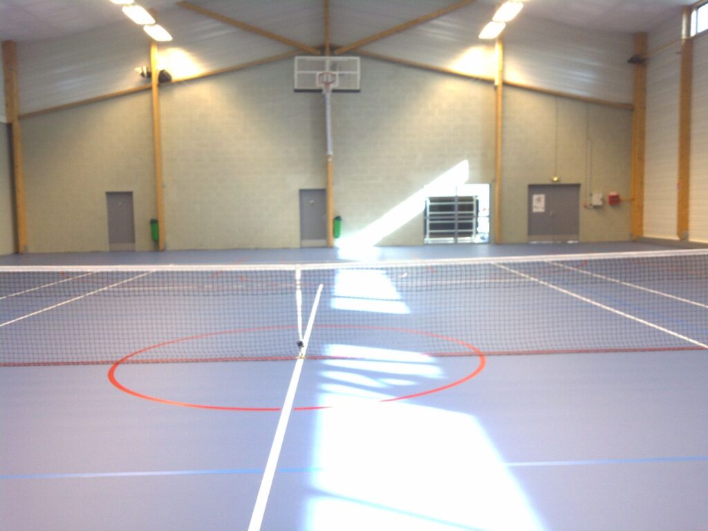 Salle de sport avec terrain de tennis intérieur.