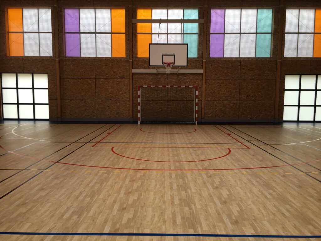Gymnase vide avec terrain de handball et panier de basket.