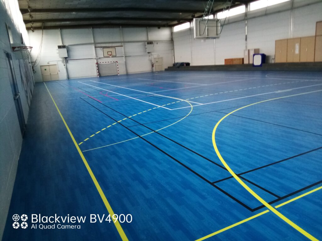 Gymnase vide avec terrain de sport marqué.