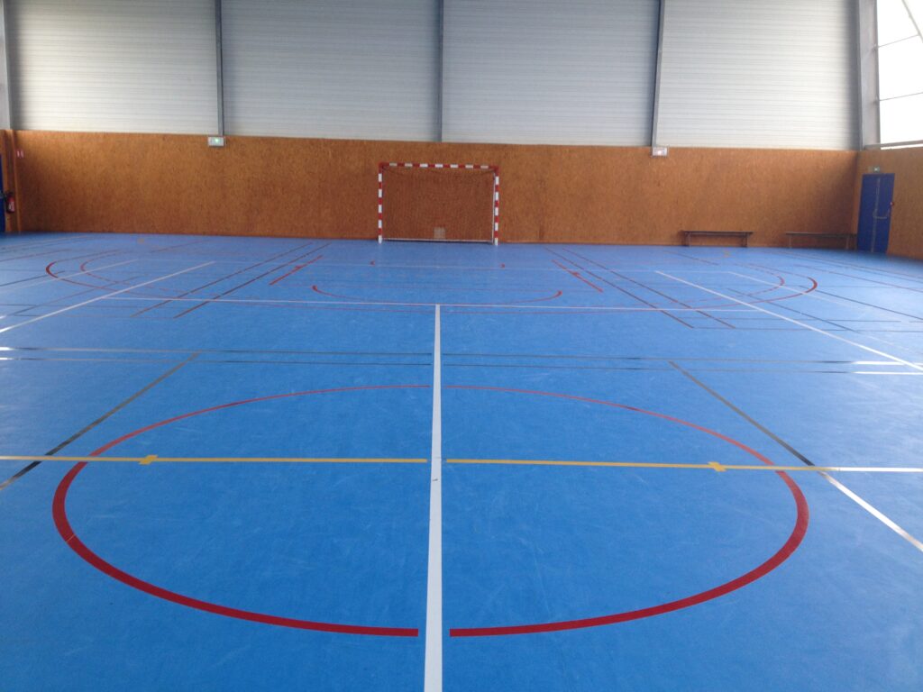 Salle multisports intérieure vide et marquages au sol.