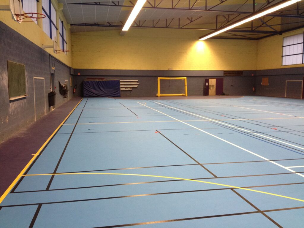 Gymnase vide avec terrain de sport marqué.