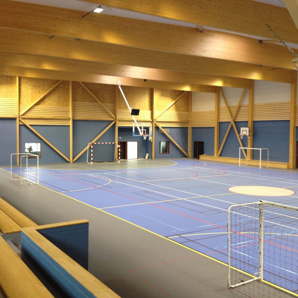 Gymnase intérieur avec terrain de basket et de handball.