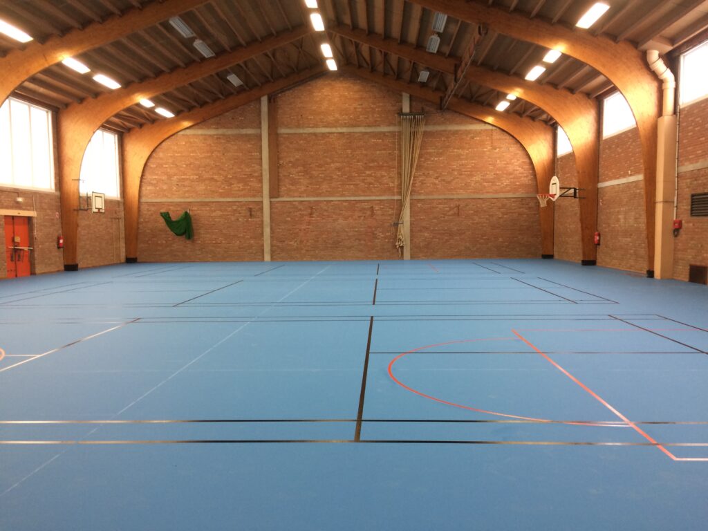 Gymnase intérieur vide avec terrain de sport marqué.