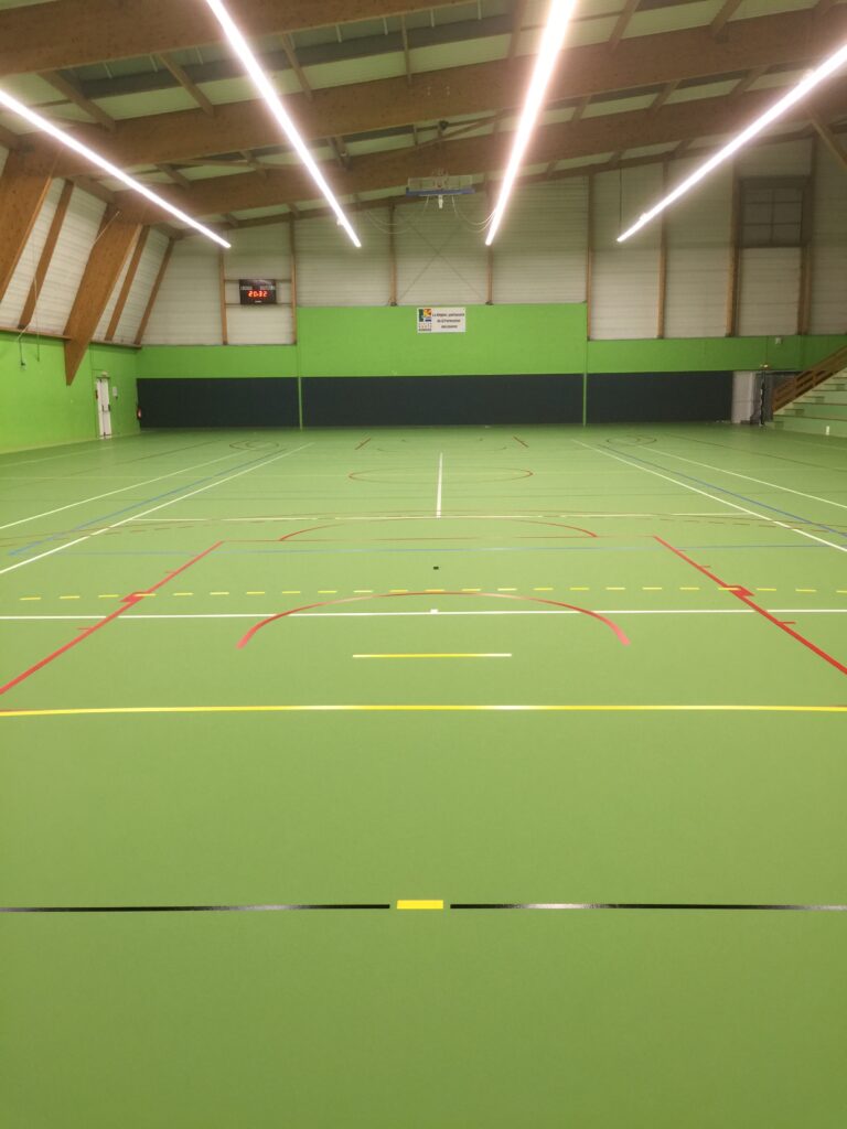 Salle multisports intérieure avec terrains de badminton.