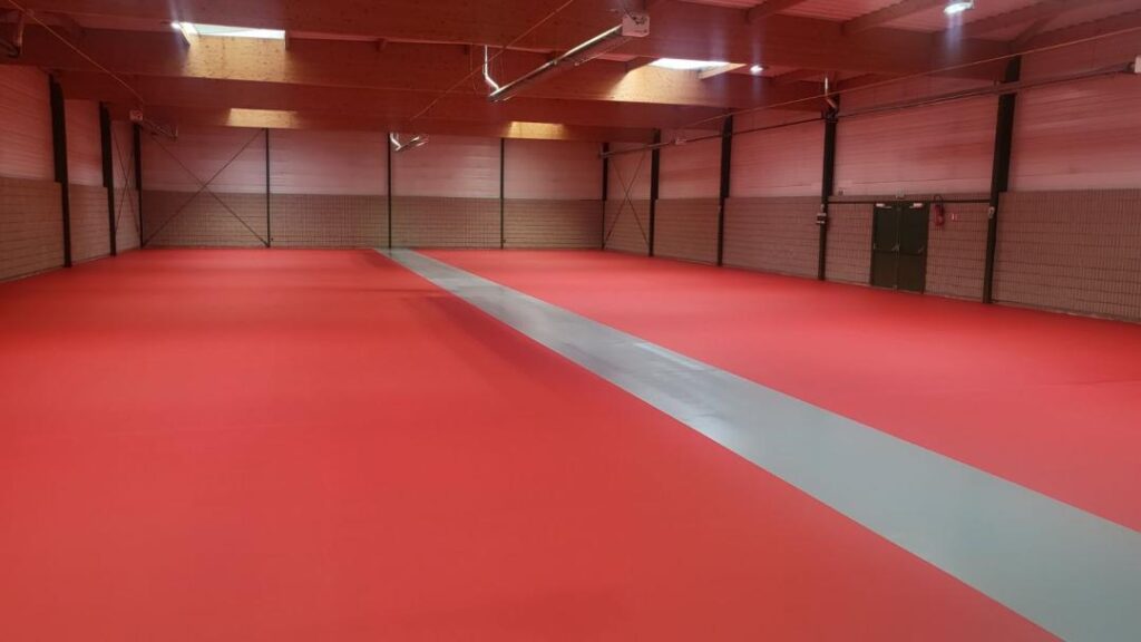 Salle d'arts martiaux avec tatami rouge.