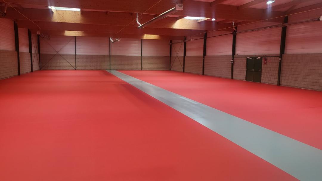 Salle d'arts martiaux avec tatami rouge.