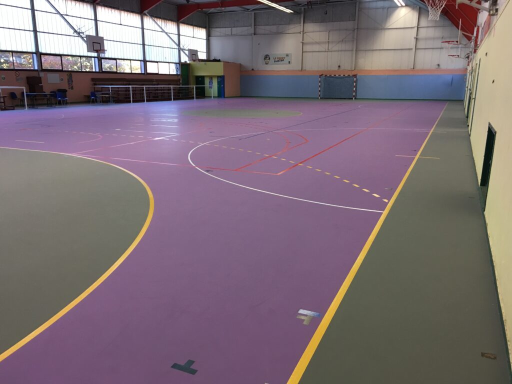 Gymnase intérieur vide avec terrain de sport.