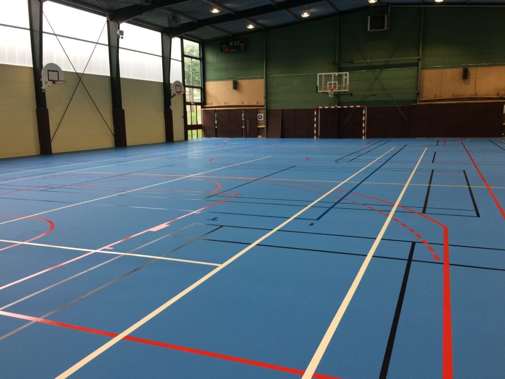 Gymnase vide avec terrain multisports tracé.