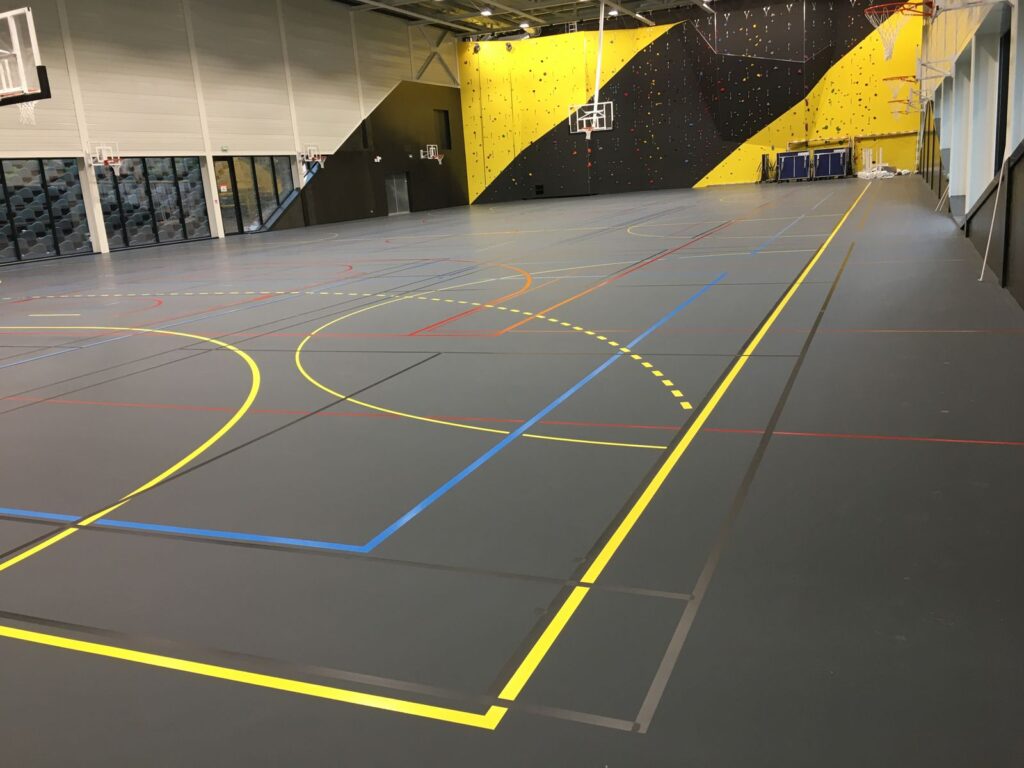 Salle de sport polyvalente avec mur d'escalade.