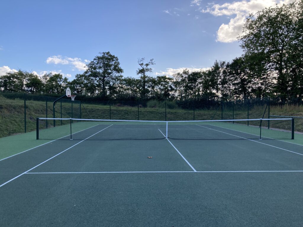 Terrain de tennis extérieur vide en journée.