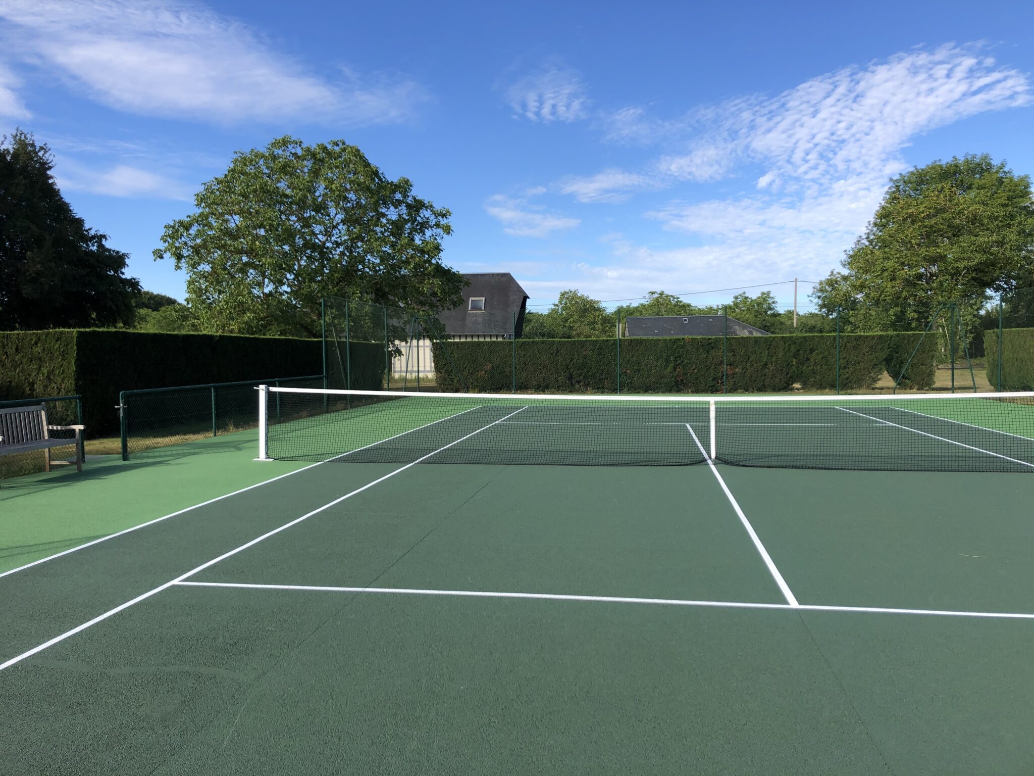 tennis beton poreux granchain (27) Terrain de tennis extérieur en journée.