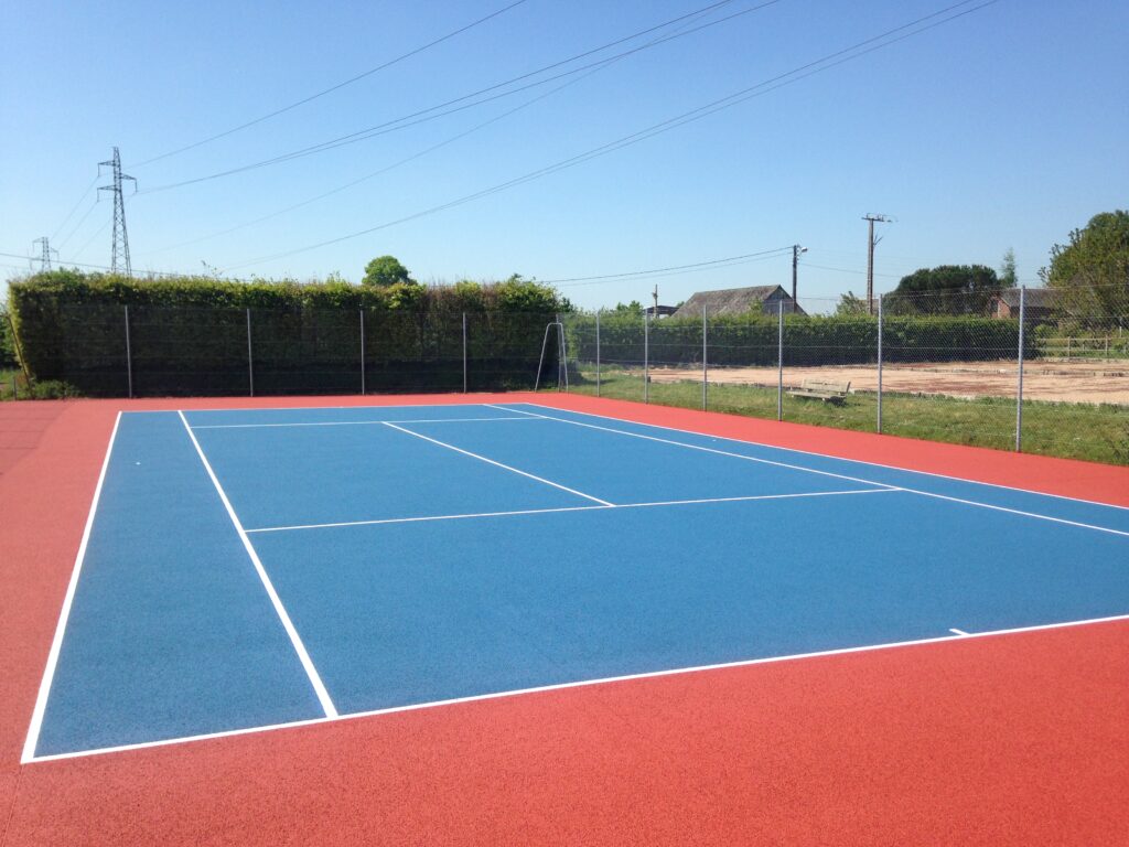 Terrain de tennis extérieur, surface bleue et rouge.