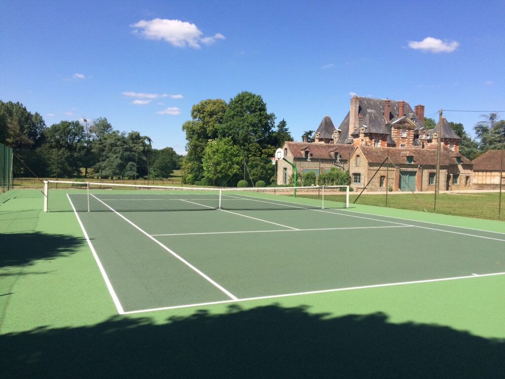 Terrain de tennis et manoir en arrière-plan.