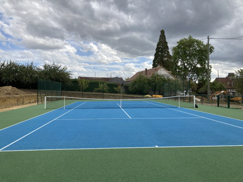 Terrain de tennis extérieur, ciel nuageux.