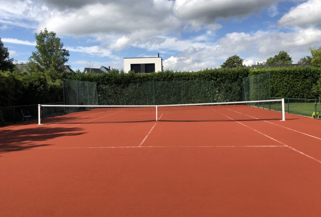 Terrain de tennis extérieur en journée.