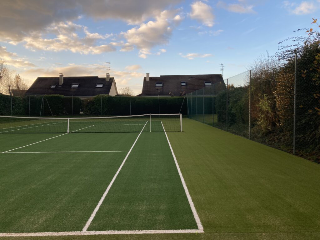 Terrain de tennis extérieur, résidences, ciel nuageux.