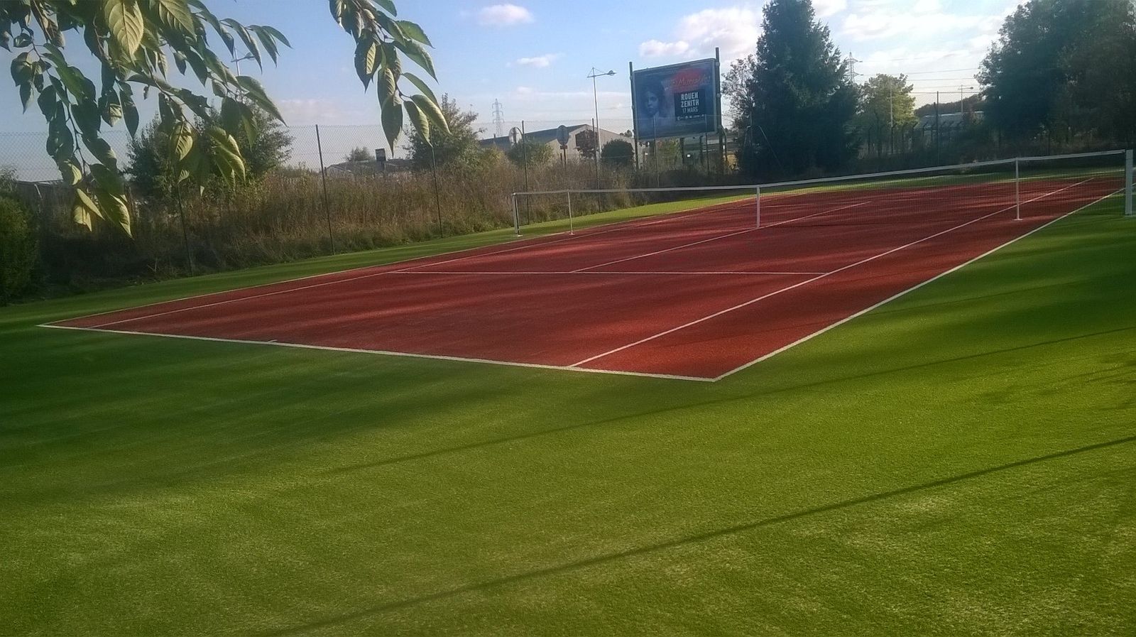 tennis gazon synthetique sable grand couronne (76) Terrain de tennis extérieur, sol rouge et vert.