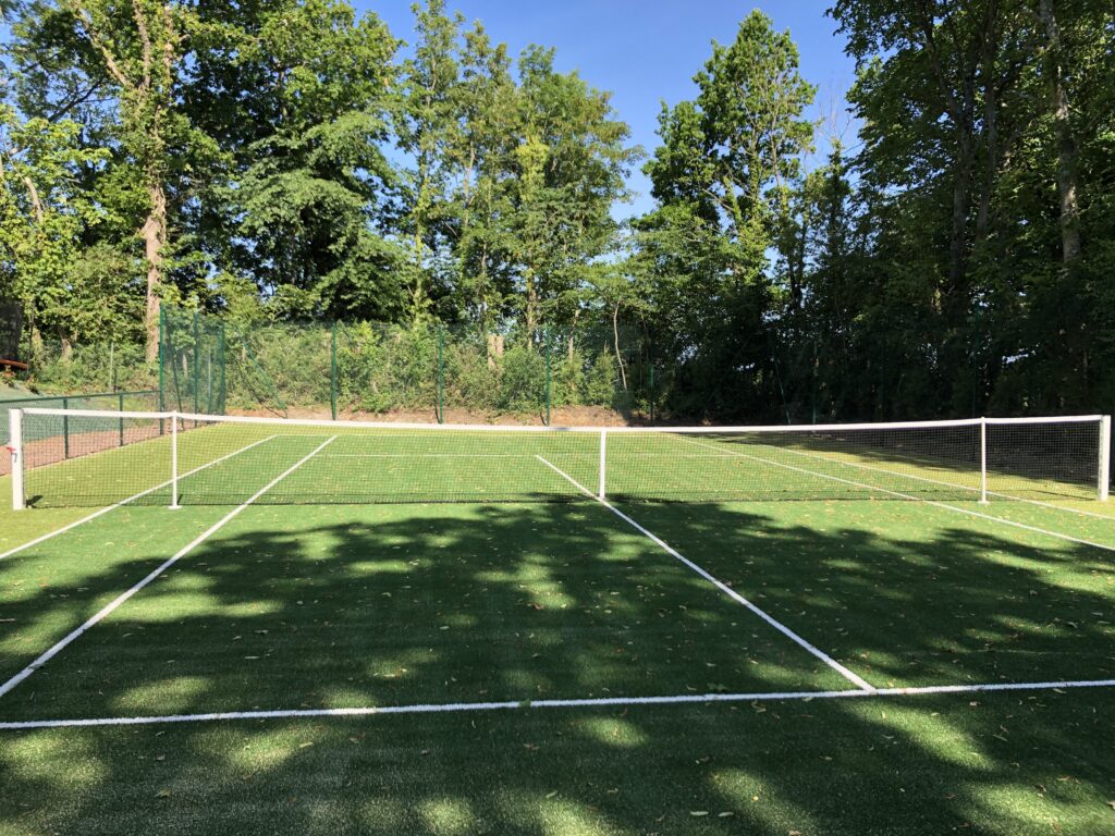 Terrain de tennis en extérieur, forêt alentour.