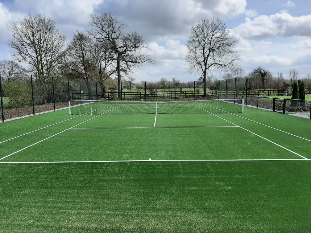 Terrain de tennis extérieur verdoyant.