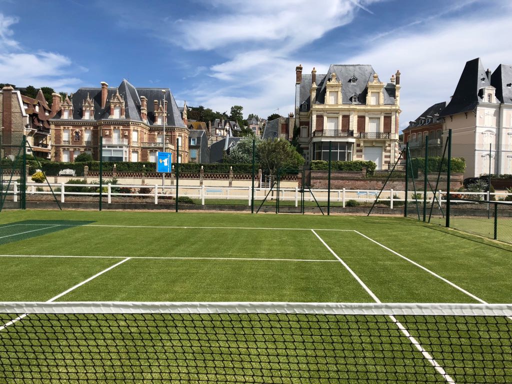 Terrain de tennis et villas luxueuses en arrière-plan.