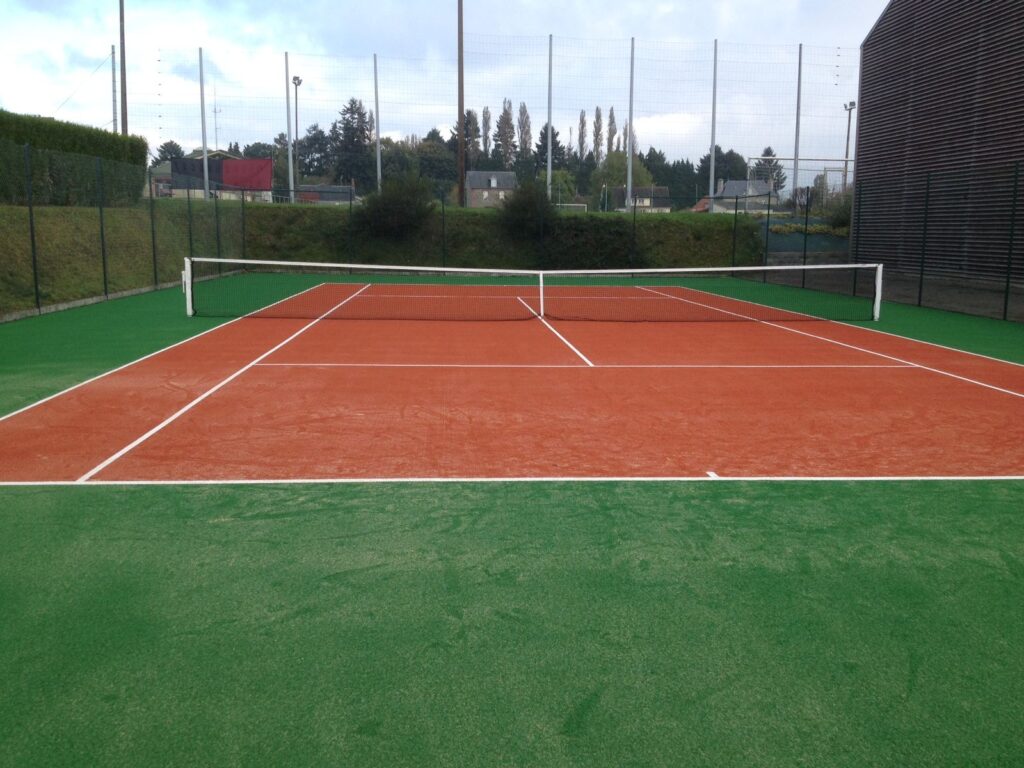 Terrain de tennis extérieur, surface en terre battue.