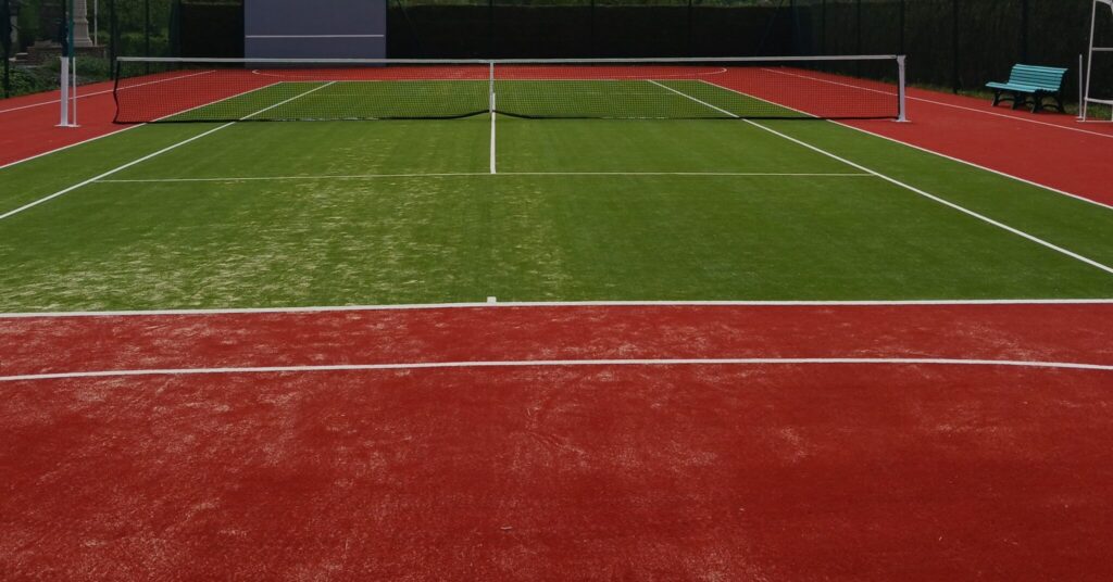 Court de tennis extérieur, terrain rouge et vert.
