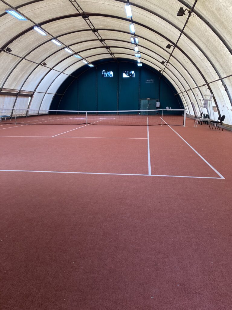 Terrain de tennis couvert en intérieur.