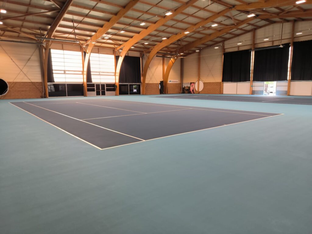 Salle de sport avec terrain de tennis intérieur.