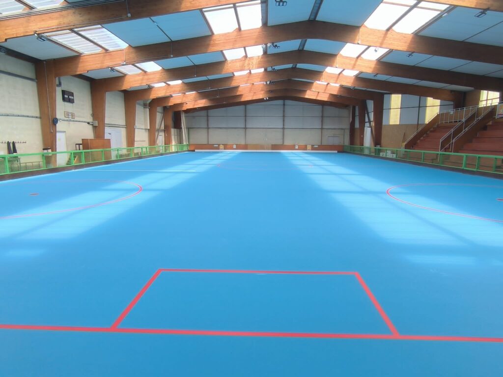 Gymnase vide avec terrain de sport bleu.