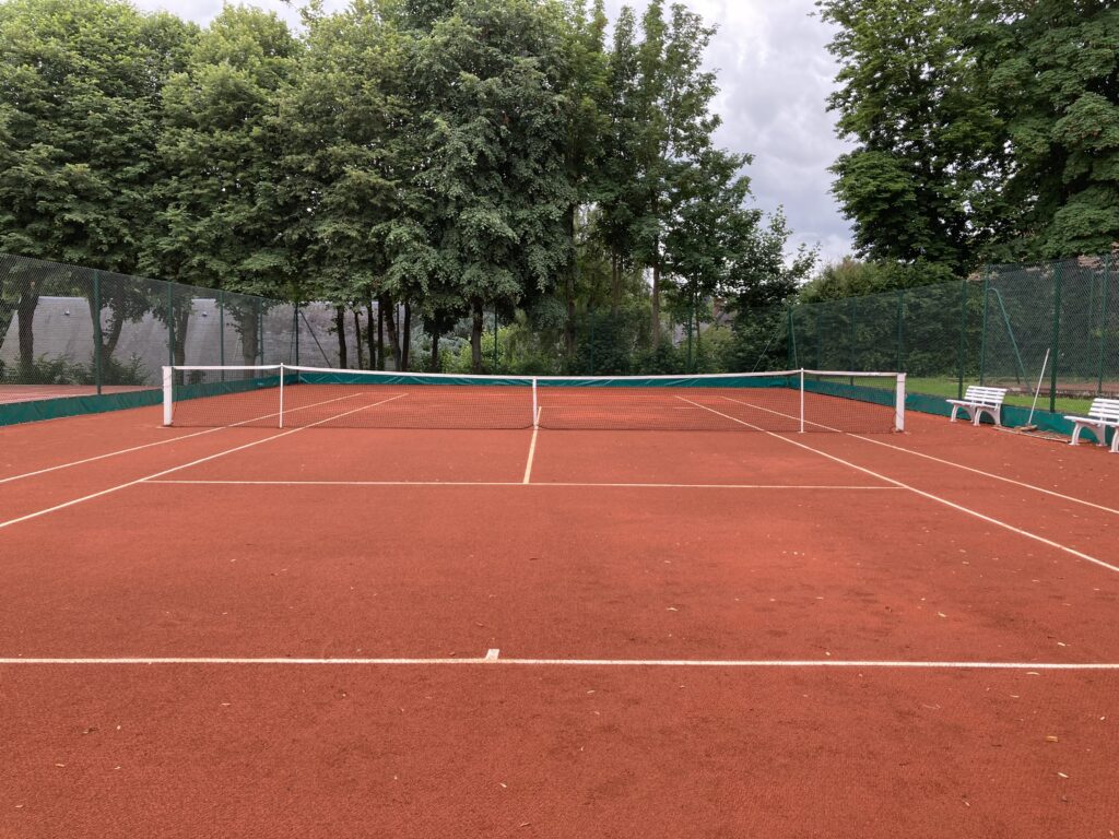 Terrain de tennis vide en terre battue.